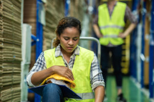Young female warehouse worker staff feeling sad and upset while sitting on the floor of the storehouse due to been fired from job cause by company bankruptcy from coronavirus pandemic.
