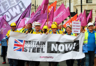 A photograph of Community Trade Unions steelworkers, marching in London, holding a Britain, We Need Our Steel NOW banner.