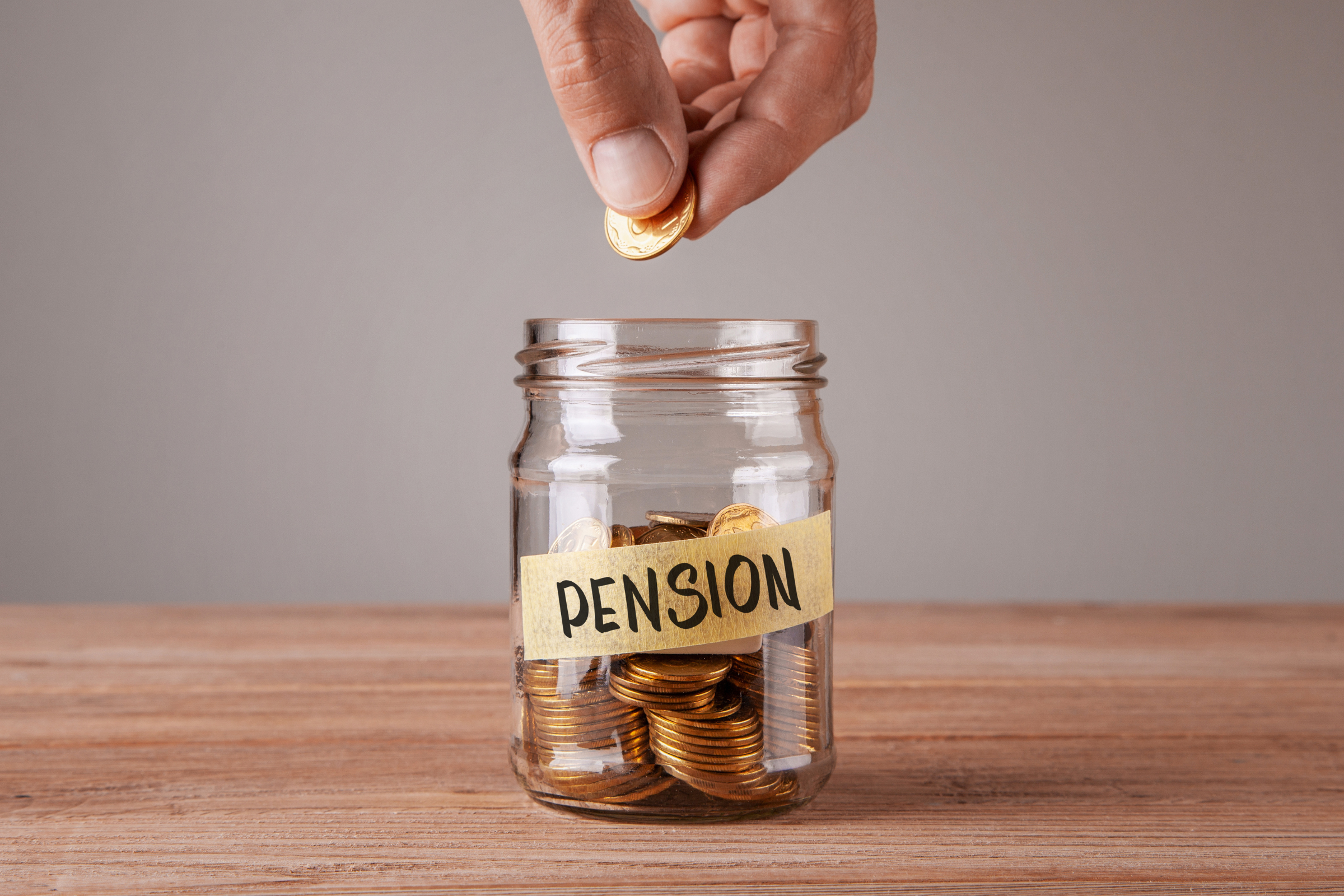 A photo of a person putting a penny in a jar with the label "pension".